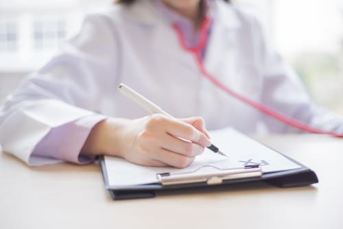 врач-нарколог на дому пишет ручкой на планшете